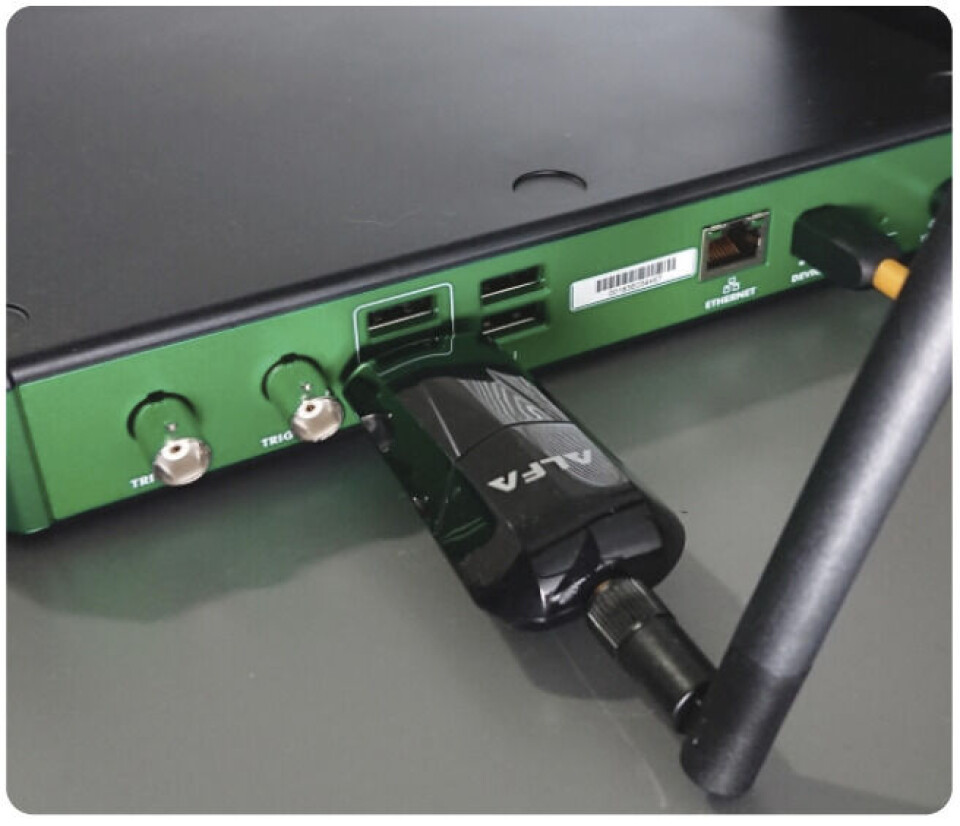 Figur 4: En USB Wi-Fi-dongle koblet til på baksiden av ADP3450 for fjerntesting og kontroll. Figur 4: En USB Wi-Fi-dongle koblet til på baksiden av ADP3450 for fjerntesting og kontroll.
