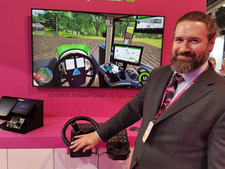 Digital farming: Tria bruker her en kombinasjon av spillteknologi, HMI-løsninger og kortmoduler med AI-akselerasjon for å demonstrere et komplett scenario for en landbruksmaskinsimulator som Alex Woods her viser frem, med fullt fungerende ratt, knapper, skjermer og joystick.