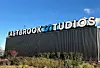 Fasade med Eastbrook Studios-logo over en stor studiohall og grønt område foran.